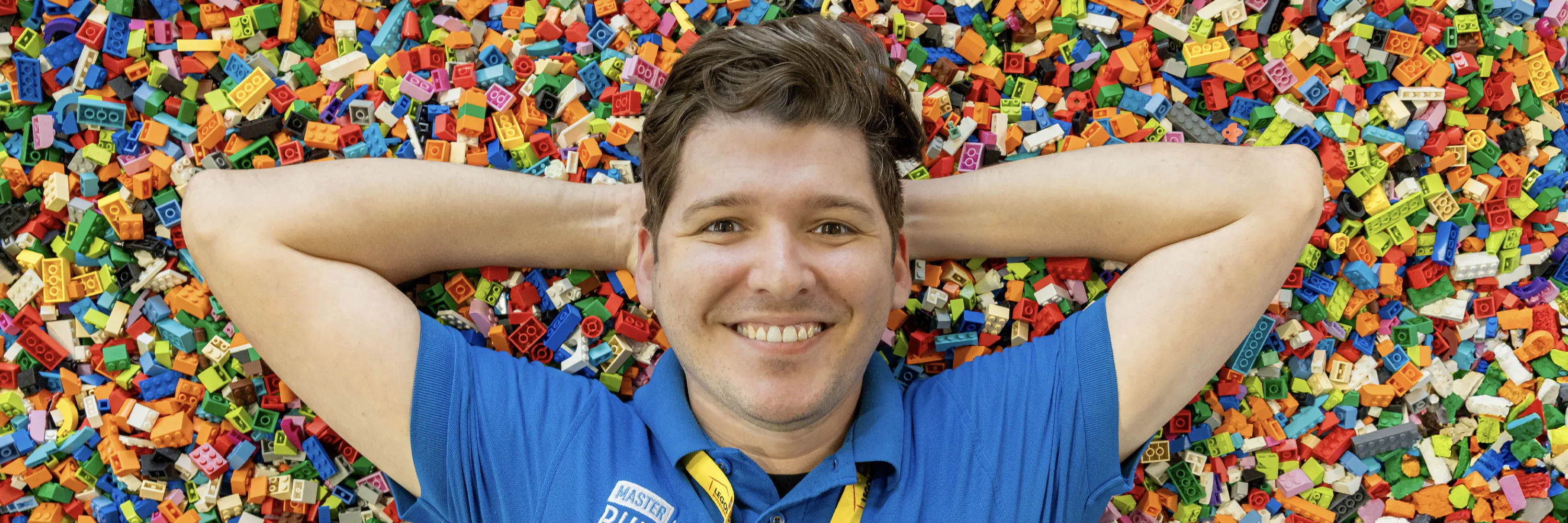 Modellbaumeister Alec liegt auf einem Stapel LEGO Steine