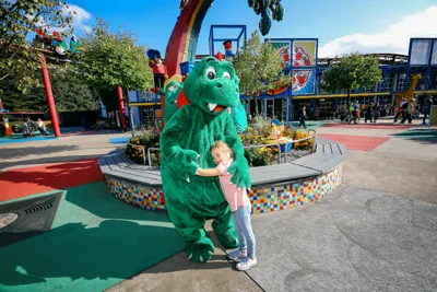 A girl hugs park dragon Olli at LEGOLAND Deutschland