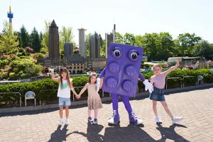 Children in LEGOLAND with large LEGO brick figure in purple color