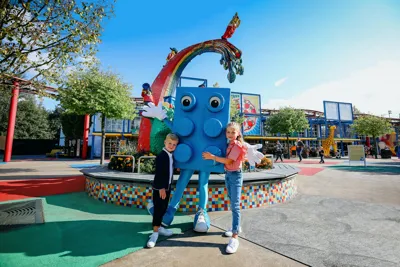 Walking character Blue Brick is hugged by two kids at LEGOLAND Deutschland