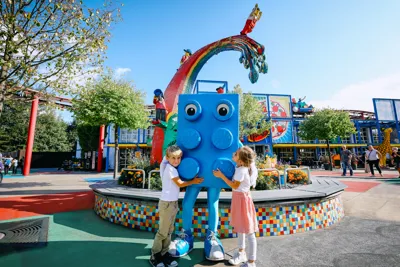 Walking character Blue Brick is embraced by two children at LEGOLAND Deutschland