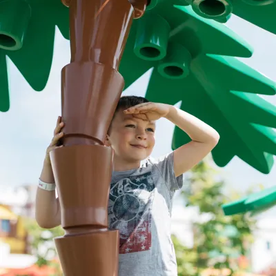 LEGOLAND Deutschland opening hours with boy under a LEGO palm tree