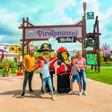 Family and LEGO pirate figures in front of the Pirate Island Hotel in the LEGOLAND Holiday Village