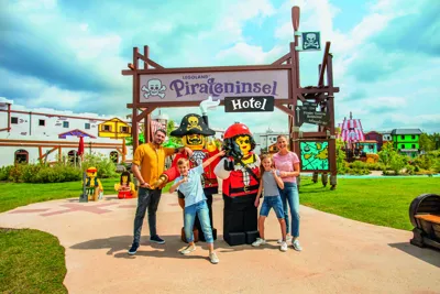 Family and LEGO pirate figures in front of the Pirate Island Hotel in the LEGOLAND Holiday Village