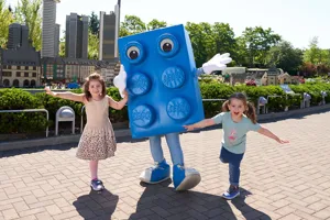 Two children in LEGOLAND with large LEGO brick figure in blue color