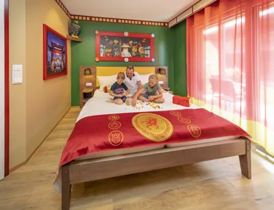 Father with two children on bed in NINJAGO accommodation room in LEGOLAND vacation village